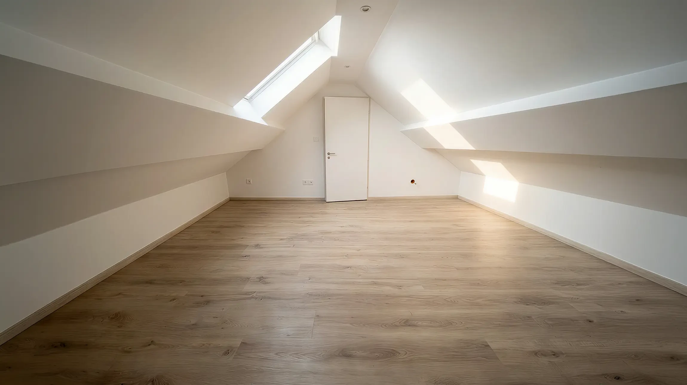 Une main tenant un couteau à enduire applique un enduit de lissage blanc sur un mur intérieur, à la jonction entre une surface grise et blanche