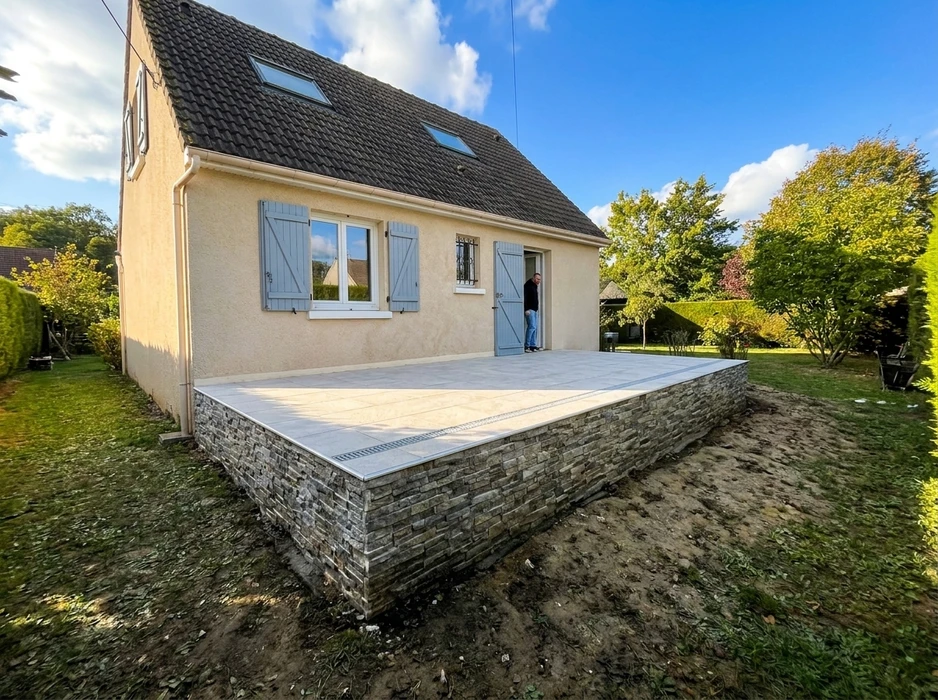 Chantier extérieur avec ouvrier en salopette bleue lissant une dalle de béton fraîchement coulée à l'aide d'une taloche