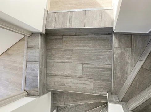 Homme en t-shirt blanc installant du parquet en bois dans une pièce lumineuse avec murs blancs et fenêtre