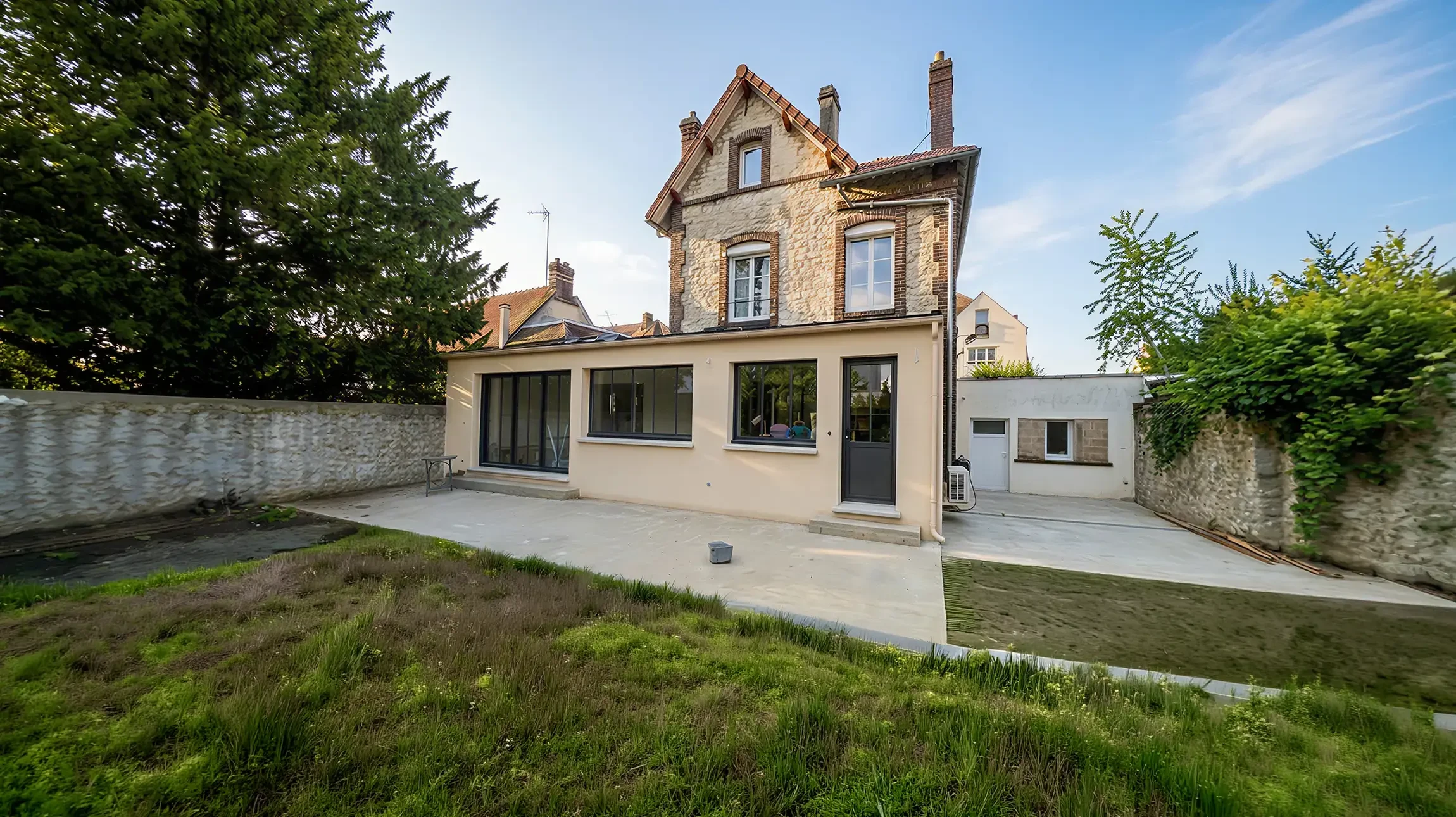 Terrasse couverte d'une maison contemporaine avec salon de jardin en résine tressée